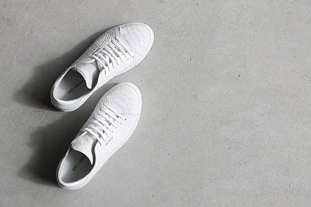 pair of white low-top shoes on gray floor thumbnail