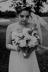 grayscale photo of woman wearing strapless wedding gown holds flower bouquet thumbnail
