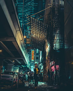 woman holding smartphone between buildings during nighttime thumbnail