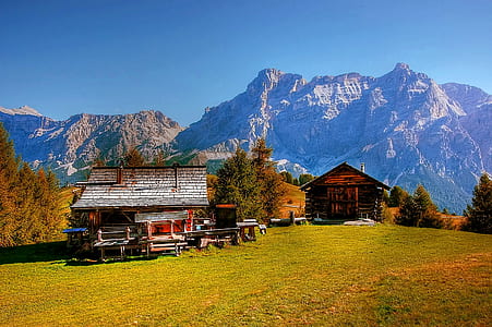 red and gray wooden house near mountain under blue sky thumbnail