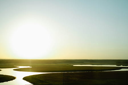 aerial photography of green grass field near body of water at daytime thumbnail