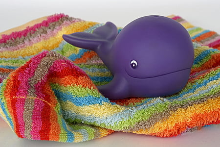 purple plastic whale toy on multicolored towel thumbnail