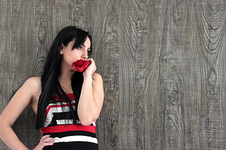 woman in red, white, and black strapless outfit holding red flower thumbnail