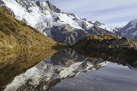 mirror photography of hills coated with snow during daytime thumbnail