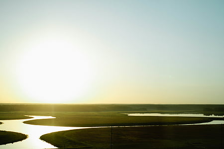aerial view of lake and green fields under blue sky thumbnail