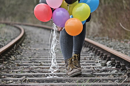 selective focus photography of person walking on train rail while holding balloons thumbnail