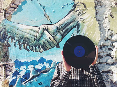 man holding vinyl in front of two person shaking their hands painting thumbnail