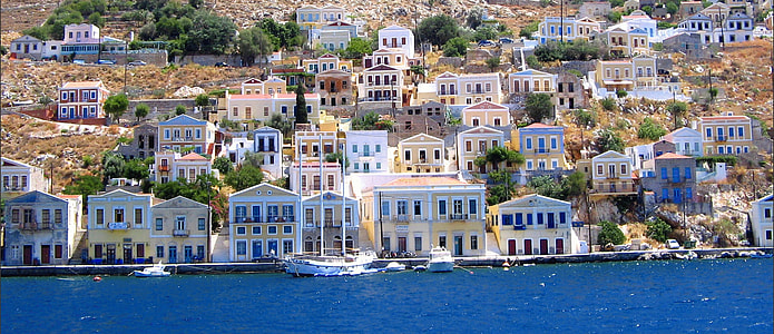 town by body of water with boat photo during daytime thumbnail