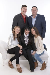 two men behind three women sitting on sofa thumbnail