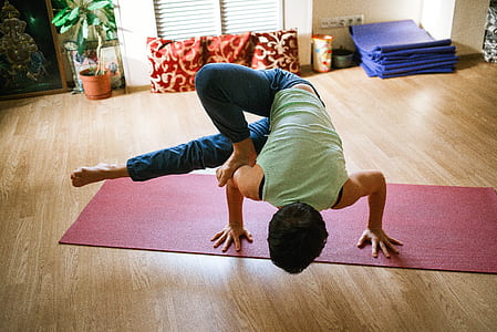 person in green sleeveless shirt doing yoga on red yoga mat thumbnail