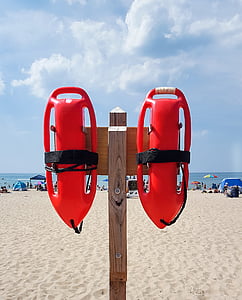 two red floaties hanging on brown wooden post thumbnail