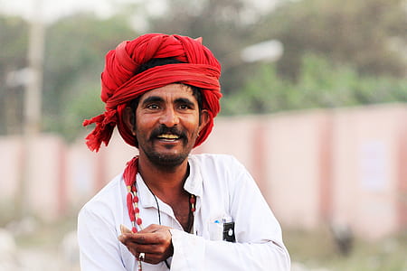 smiling man wearing red turban in shallow focus photography thumbnail