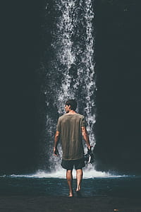 man walking towards waterfall thumbnail
