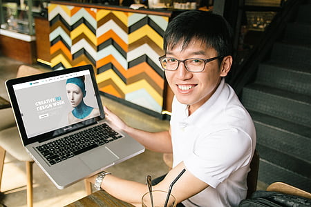man wearing white polo shirt holding MacBook Pro thumbnail