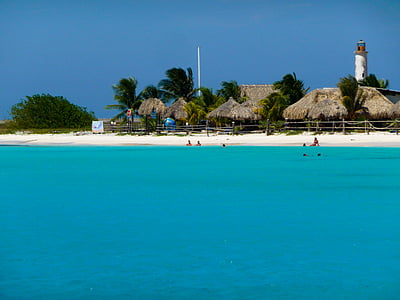 people in water and at shore near hut during daytime thumbnail