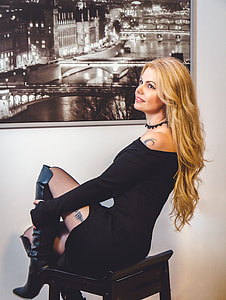 woman sitting on wooden stool near painting on wall thumbnail