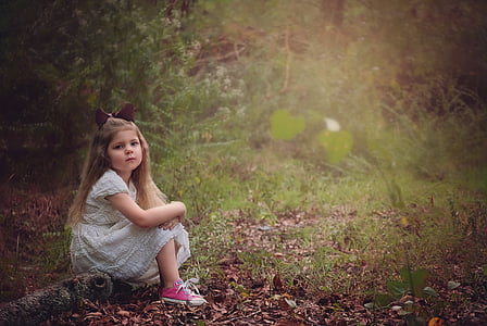 girl in gray dress sitting on tree twig in the middle of the forest thumbnail