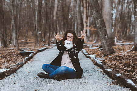 woman wearing jacket sitting on pathway during day time thumbnail