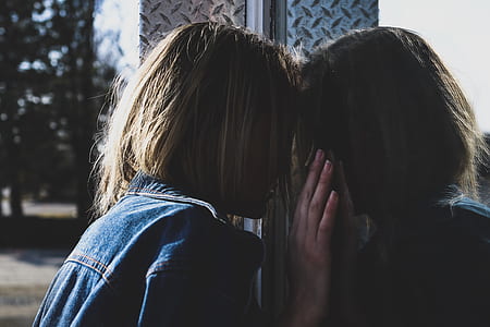 woman in blue denim jacket peeking through glass window thumbnail