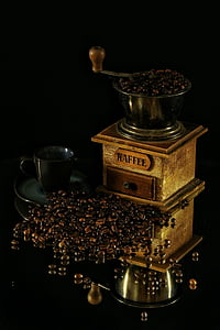 coffee beans beside black ceramic teacup and vintage manual coffee brewer thumbnail