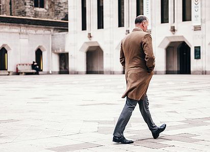 man walking toward white concrete building thumbnail