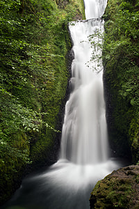 time lapse photography of waterfalls between plant covered mountains thumbnail