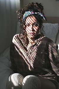 woman wearing brown flannel shirt with headband sitting on bed thumbnail