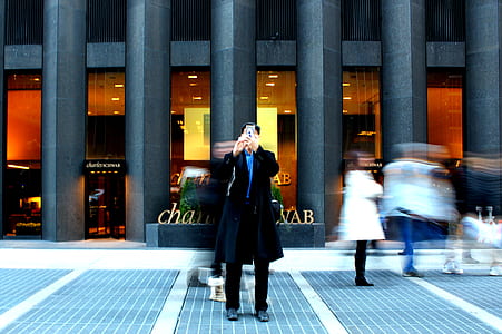 man standing front of building while holding smartphone thumbnail