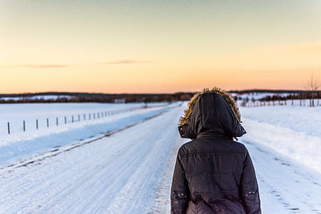 person wearing black parka standing facing snow covered road thumbnail