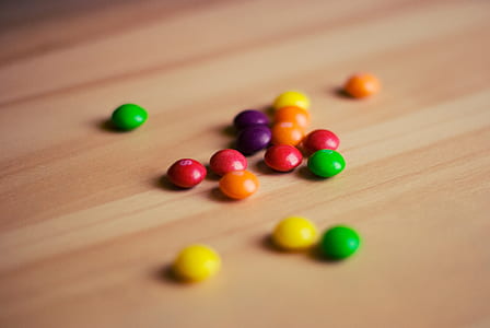 tilt shift photo of assorted-color of candies on brown wood surface thumbnail
