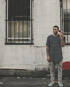man standing in front of wall holding smartphone near his ear thumbnail