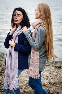 two women wearing scarves standing near body of water thumbnail