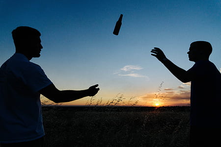 silhouette of two person tossing a bottle thumbnail