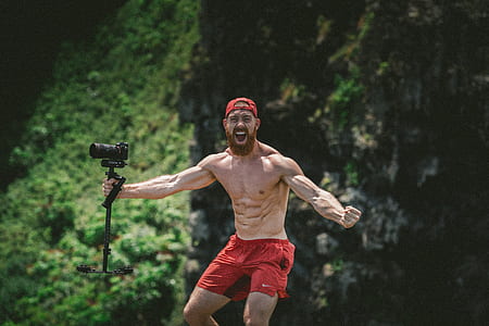 man holding DSLR camera with stabilizer while flexing muscles at daytime thumbnail