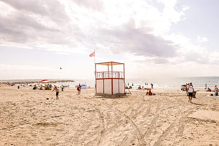 white and red lifeguard post on beach near the body of water under the white clouds at daytime thumbnail