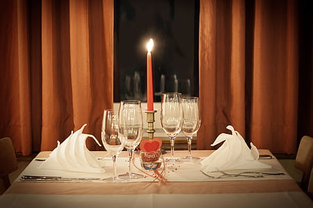 four clear flute glasses on table beside red taper candle thumbnail
