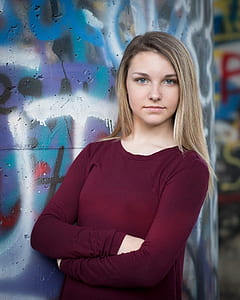 woman wearing maroon top standing beside wall thumbnail