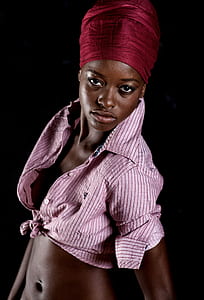 woman in pink and black pinstriped button-up collared crop-top wearing red headdress thumbnail