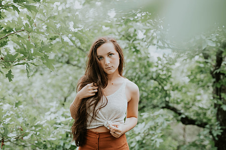woman in white sleeveless top standing near green leafed tree thumbnail