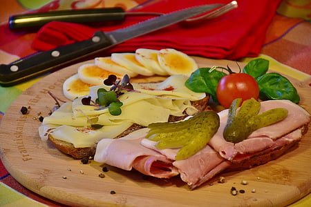sliced ham, red tomato fruit and sliced fruit on brown wooden chopping board thumbnail