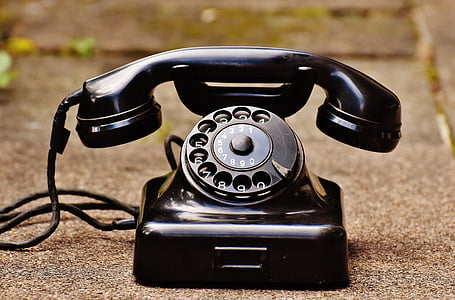 black rotary telephone on gray concrete flooring thumbnail