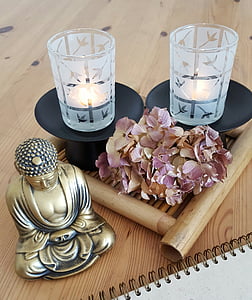 gold-colored Buddha figurine beside purple withered hydrangea flowers and two frosted glass candle holders thumbnail