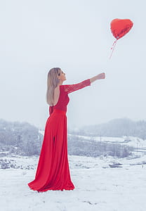 woman wearing red scoop-back dress letting go of red heart balloon thumbnail