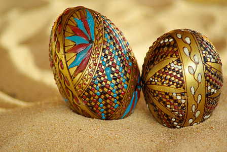 two beige-and-red decorative eggs on brown sand thumbnail