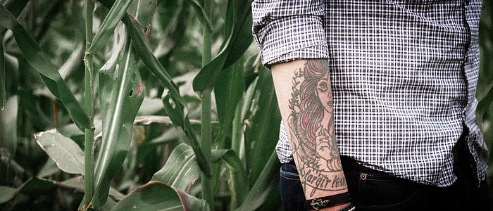 standing man with tattoo near plant thumbnail