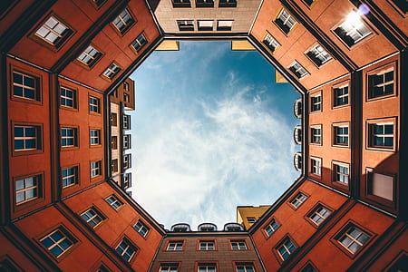 low angle photo of red brick building under blue skies forming a hexagonal pattern thumbnail