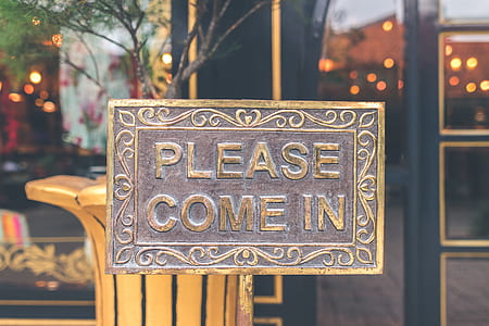 tilt-shift lens photography of rectangular brass-colored please come in signage outside restaurant thumbnail