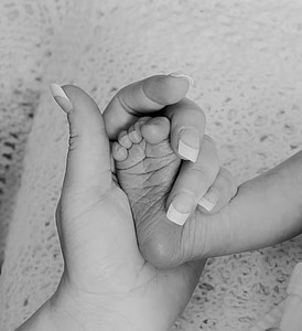 grayscale photography of woman holding baby's foot thumbnail