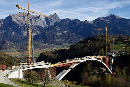 white concrete bridge across on brown and green rock formation at daytime thumbnail