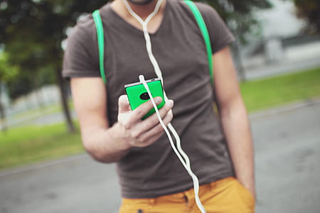 selective focus photography of man holding green smartphone thumbnail